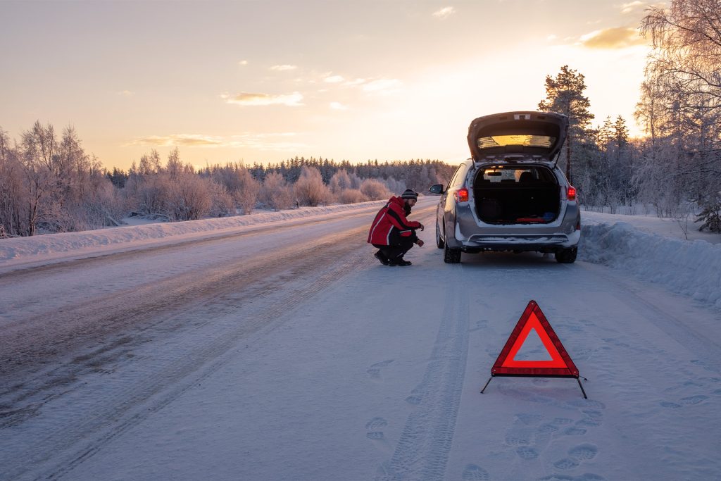 Bil i vinterlandskab med meget sne og advarselstrekant